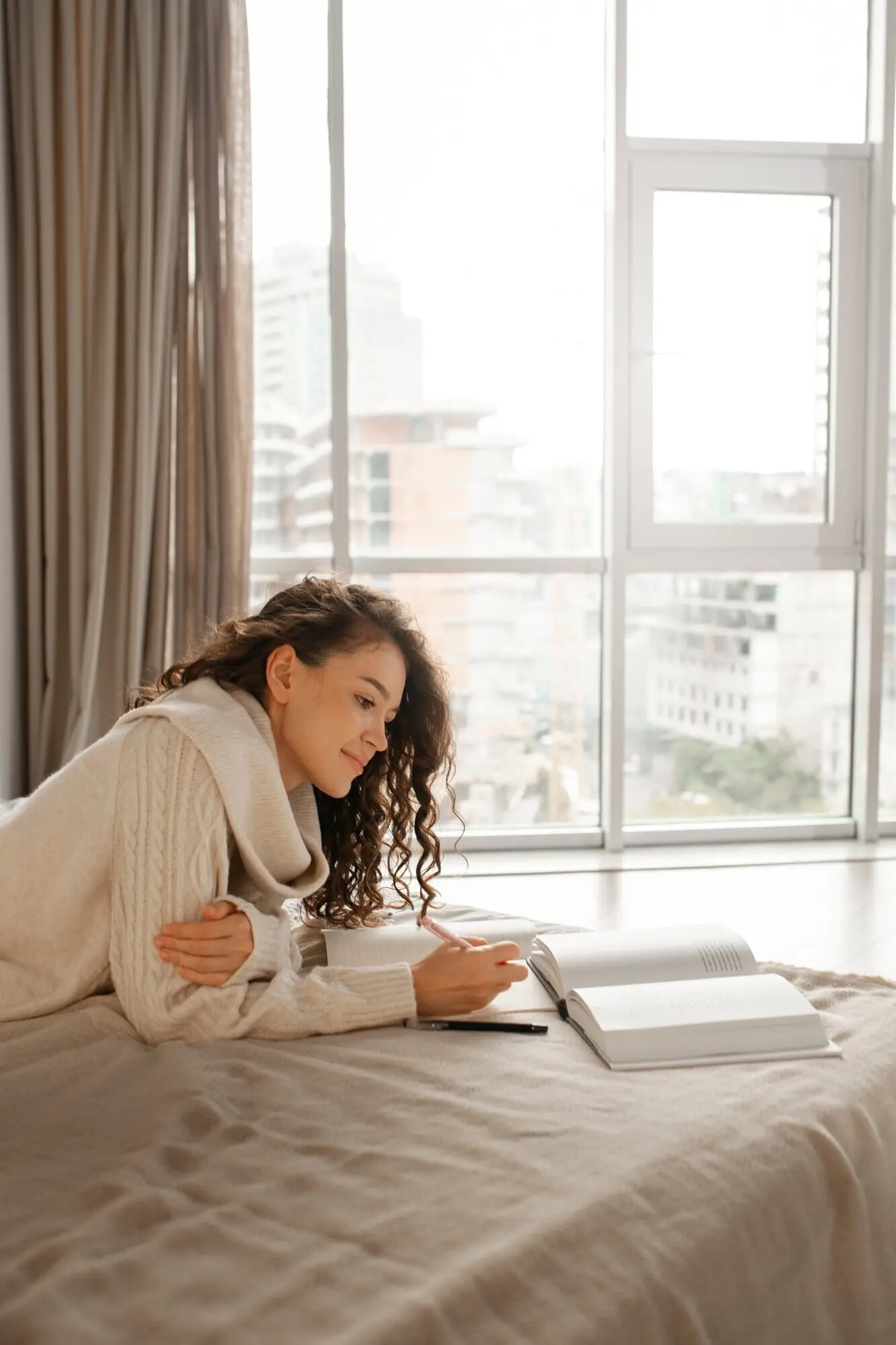A woman disconnecting from digital devices at home by reading a book in bed.