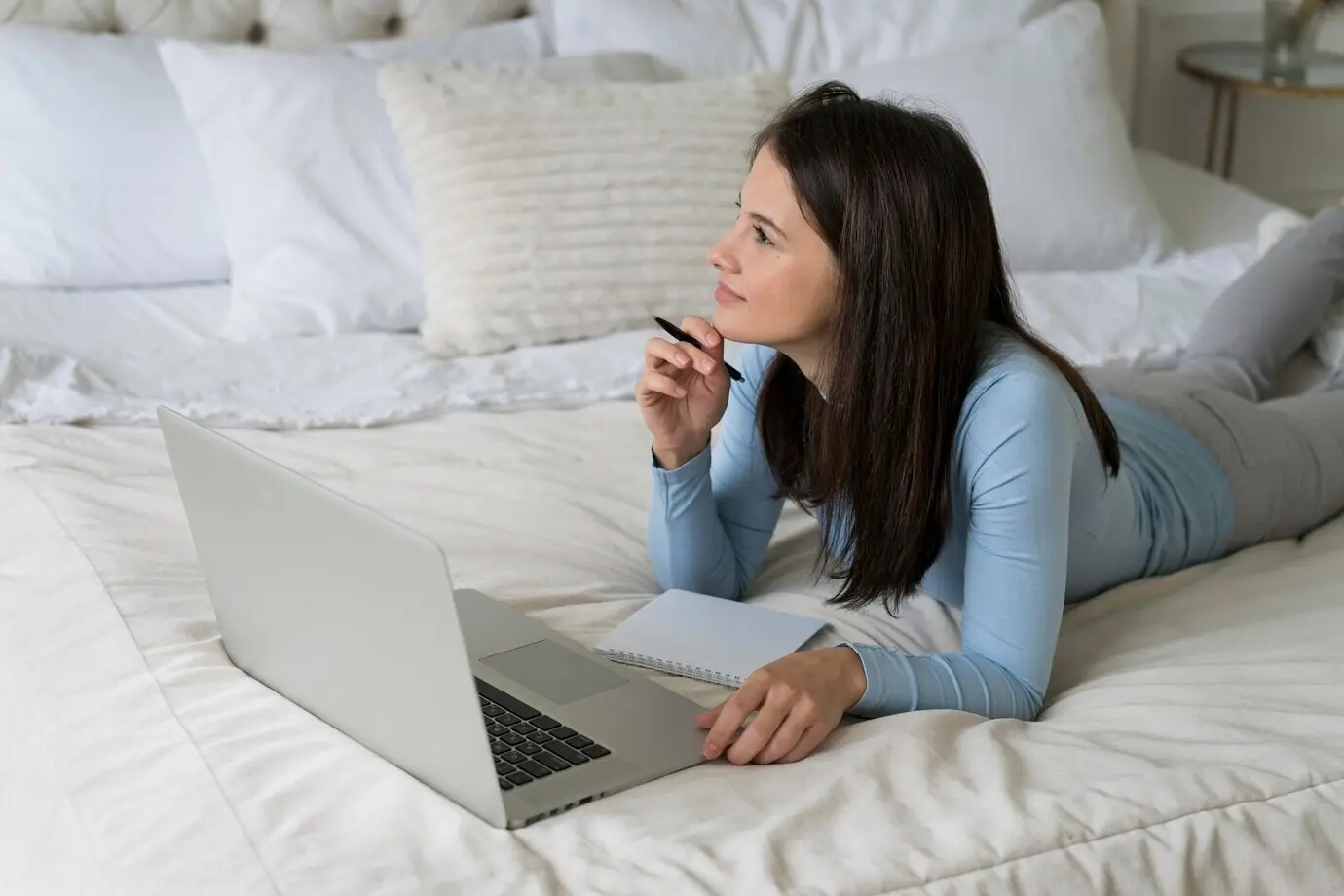 A woman remains in her bed while on a video call on her laptop.
